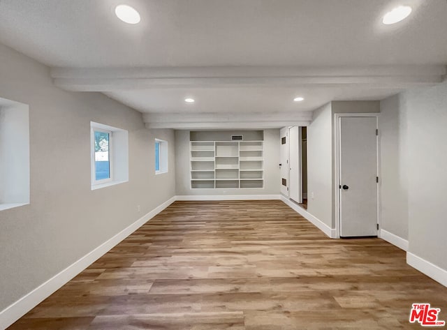 spare room featuring beamed ceiling, hardwood / wood-style floors, and built in features