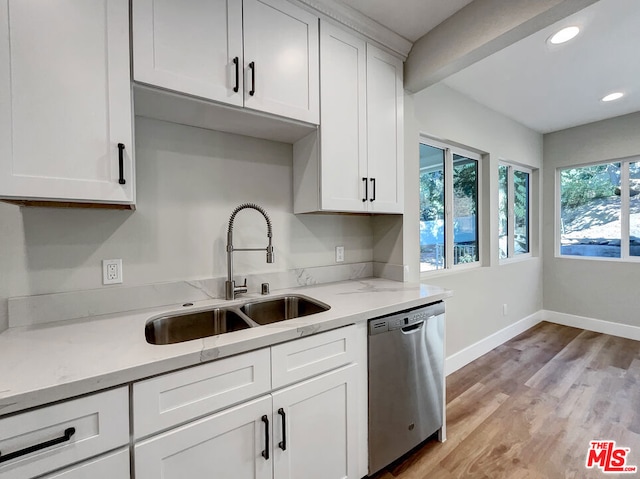 kitchen with light wood-type flooring, light stone counters, stainless steel dishwasher, sink, and white cabinetry