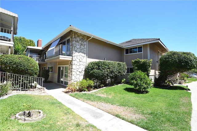 view of front of home with a front yard and a balcony