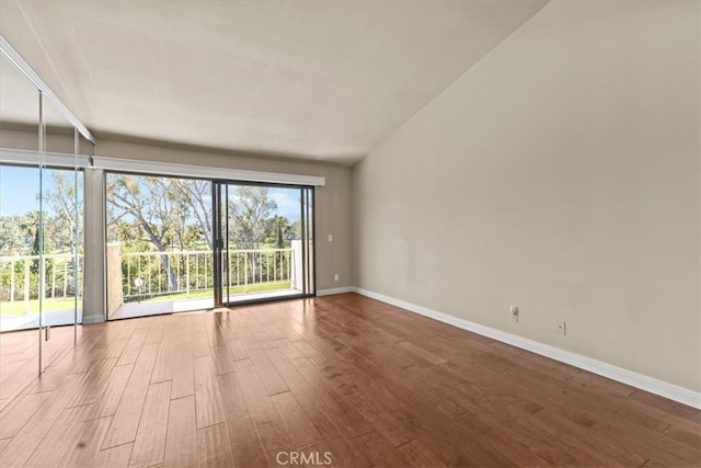 empty room with wood-type flooring and vaulted ceiling