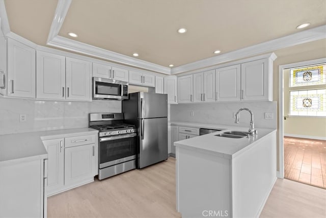 kitchen featuring appliances with stainless steel finishes, decorative backsplash, white cabinets, light wood-type flooring, and sink