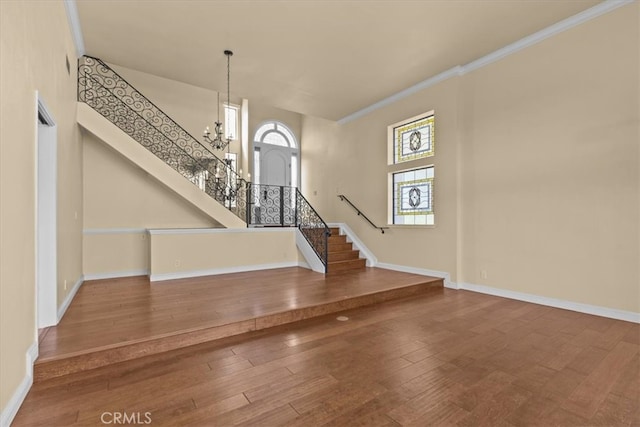 interior space with a notable chandelier, a high ceiling, hardwood / wood-style flooring, and crown molding