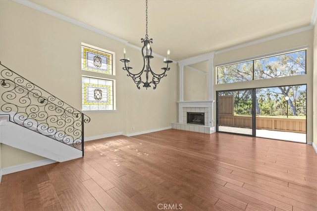 living room featuring an inviting chandelier, crown molding, a fireplace, and hardwood / wood-style floors