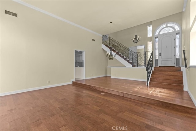 interior space with an inviting chandelier, a towering ceiling, and hardwood / wood-style floors