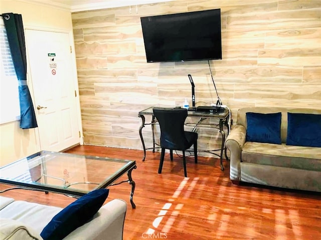 living room with ornamental molding, wood walls, and hardwood / wood-style floors