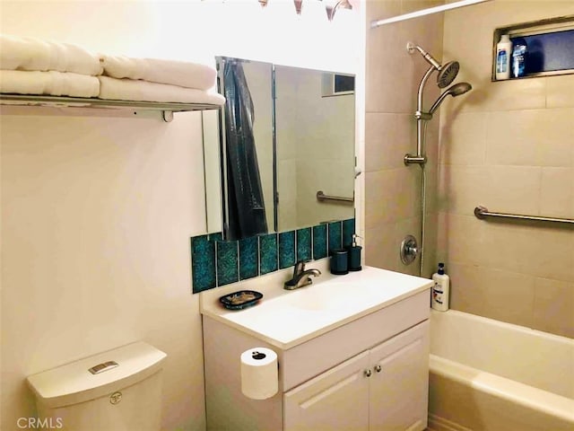 full bathroom with tiled shower / bath, vanity, and toilet