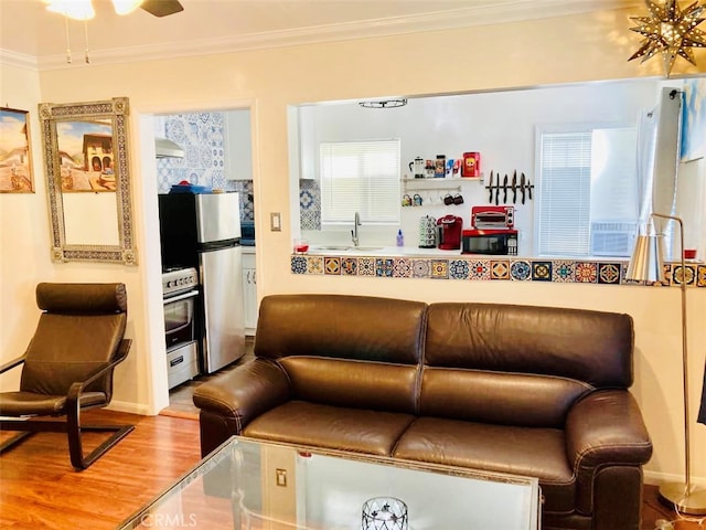 living room featuring ornamental molding, hardwood / wood-style floors, ceiling fan, and sink