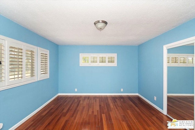 unfurnished room featuring a textured ceiling and dark hardwood / wood-style flooring