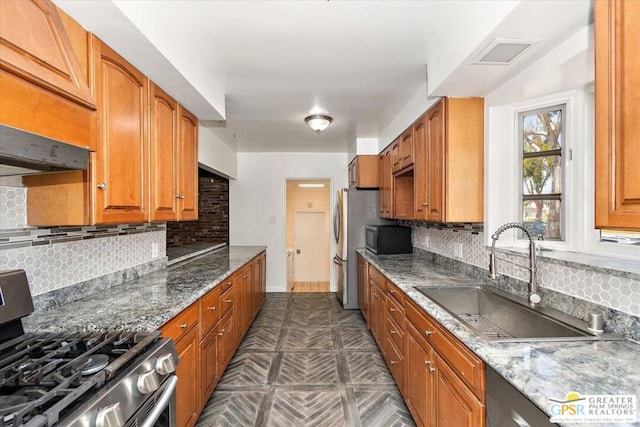 kitchen featuring dark stone countertops, backsplash, appliances with stainless steel finishes, and sink