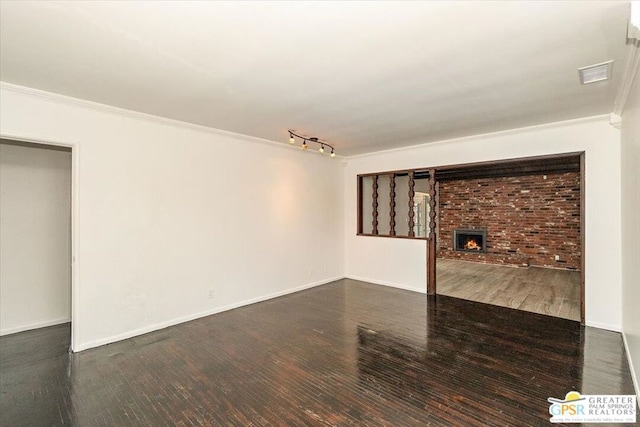 unfurnished living room with a fireplace, crown molding, dark hardwood / wood-style flooring, and rail lighting