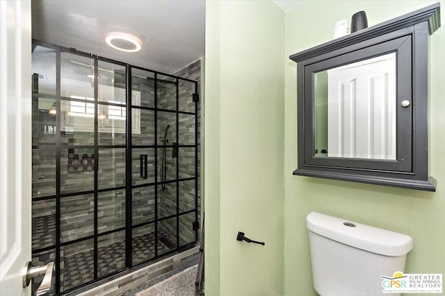 bathroom featuring a shower with door and toilet