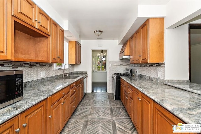 kitchen with light stone countertops, stainless steel appliances, backsplash, and sink