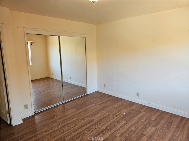 unfurnished bedroom with a closet and dark hardwood / wood-style floors