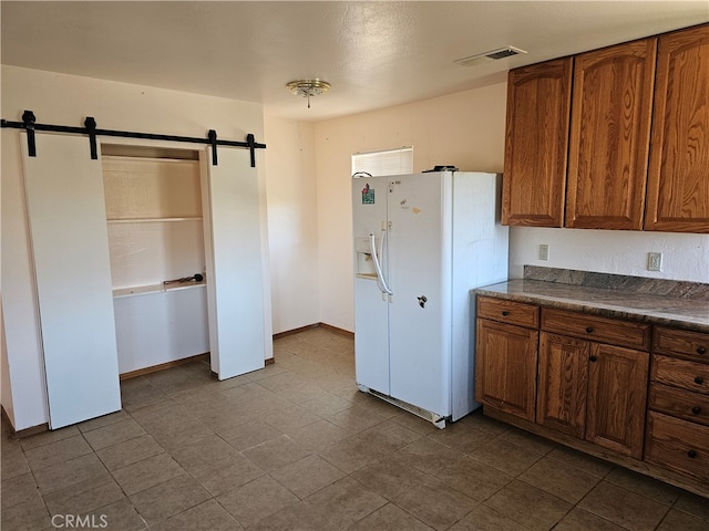 kitchen featuring white refrigerator with ice dispenser and a barn door