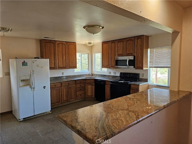 kitchen featuring a wealth of natural light, sink, black appliances, and kitchen peninsula