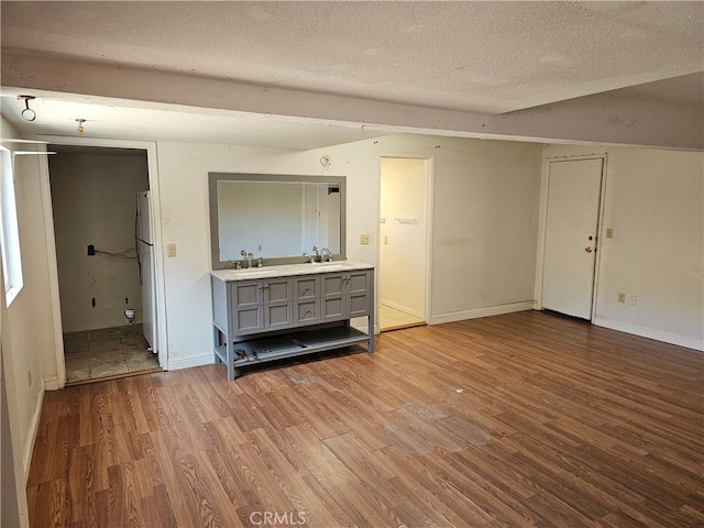 unfurnished living room featuring hardwood / wood-style floors, sink, and a textured ceiling