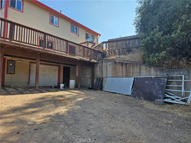 rear view of house featuring a wooden deck and a garage