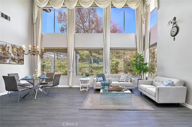 living room featuring a towering ceiling, dark hardwood / wood-style flooring, and a healthy amount of sunlight