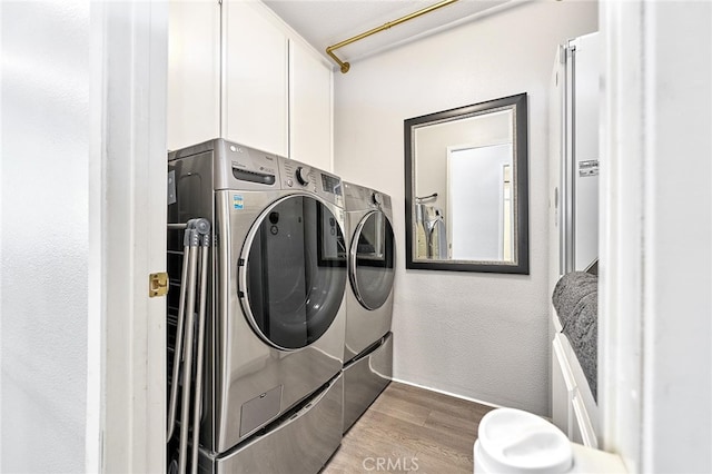 washroom with cabinets, hardwood / wood-style flooring, and washer and clothes dryer