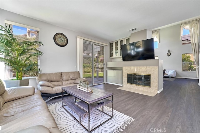 living room featuring a high end fireplace, dark wood-type flooring, and a wealth of natural light