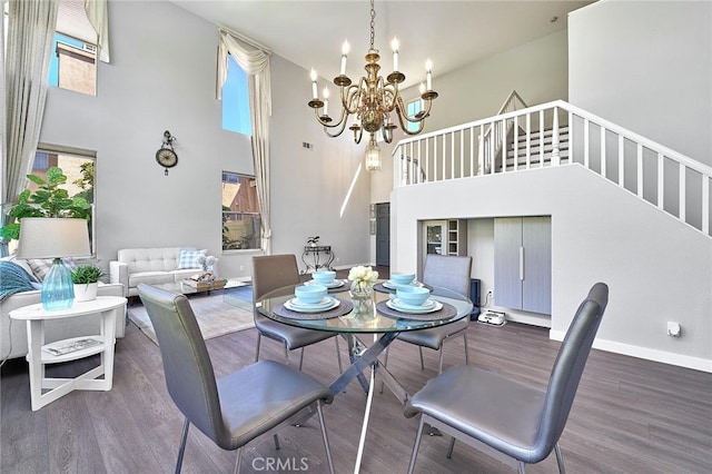 dining space with dark hardwood / wood-style floors, a high ceiling, and an inviting chandelier