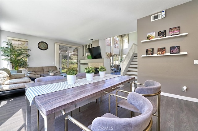 dining space with hardwood / wood-style flooring and a tile fireplace