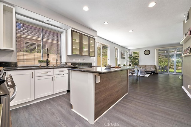 kitchen with white cabinets, a kitchen island, a textured ceiling, dark wood-type flooring, and a kitchen breakfast bar