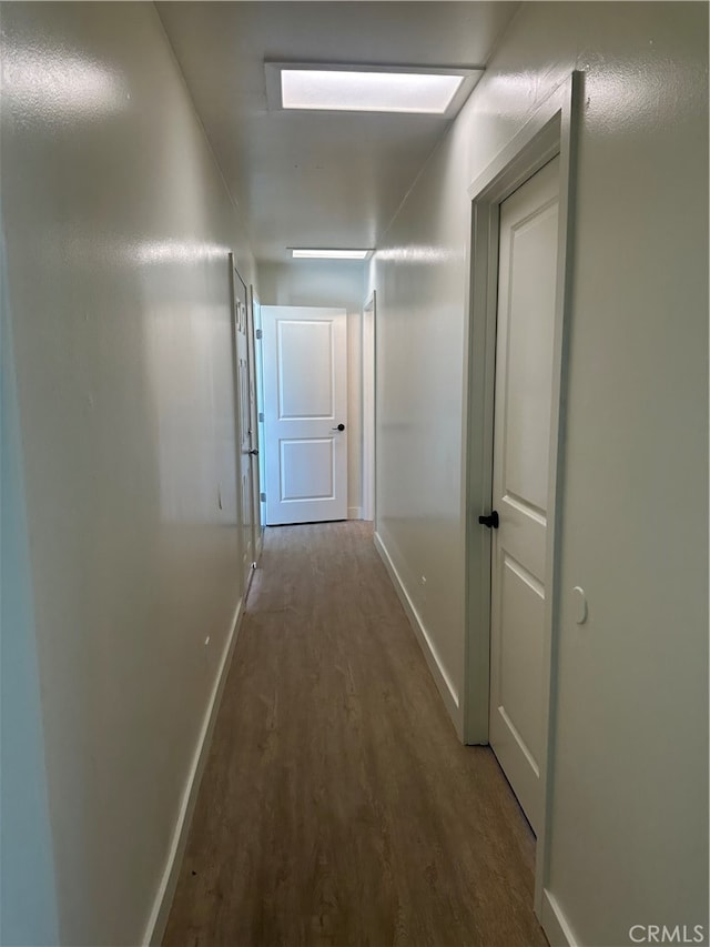 corridor with wood finished floors and baseboards