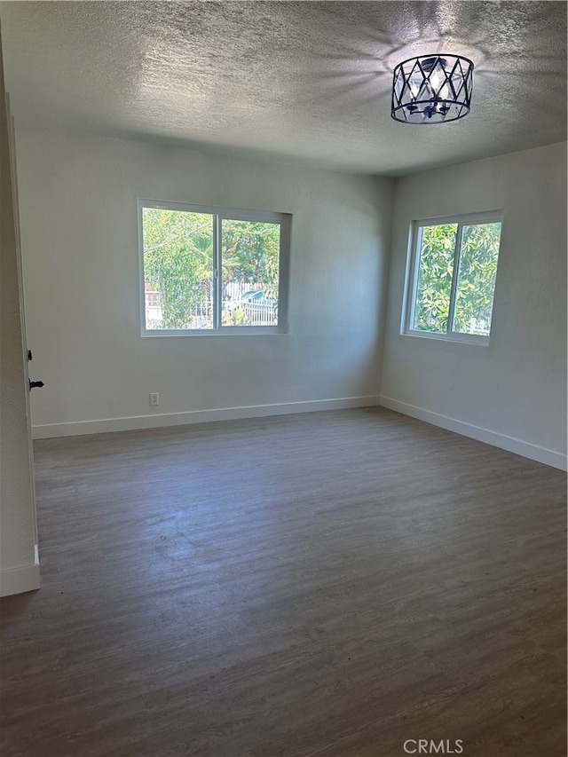 unfurnished room with baseboards, dark wood finished floors, and a textured ceiling