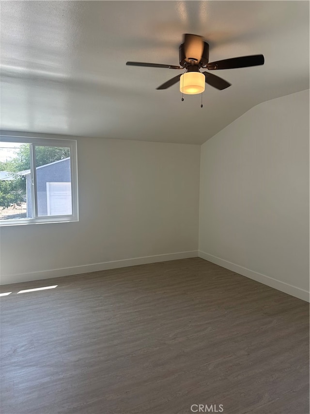 spare room featuring ceiling fan, vaulted ceiling, baseboards, and dark wood finished floors