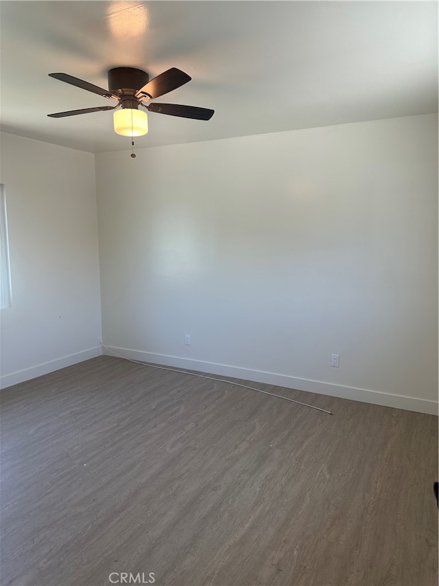 unfurnished room with ceiling fan, dark wood-style flooring, and baseboards