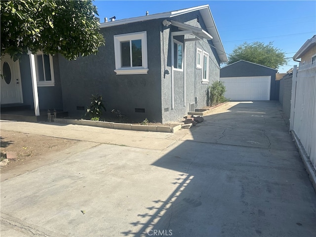 view of side of property with an outbuilding, crawl space, fence, and stucco siding