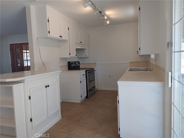 kitchen with kitchen peninsula, sink, stainless steel electric range, white cabinetry, and light tile patterned flooring