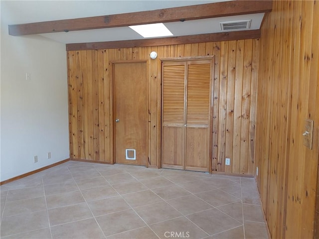 spare room featuring light tile patterned floors and wooden walls