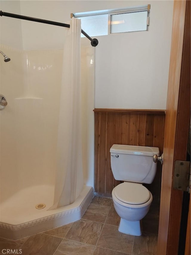 bathroom featuring wood walls, curtained shower, and toilet