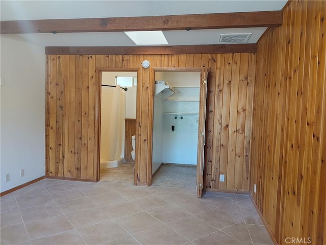 tiled empty room with a skylight and wood walls