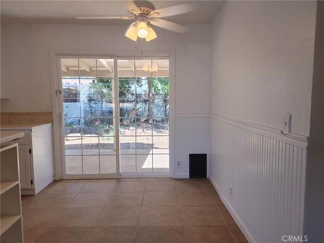 unfurnished dining area featuring ceiling fan and light tile patterned floors