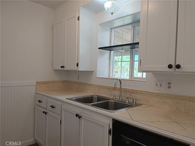 kitchen with white cabinets, tile counters, dishwasher, and sink