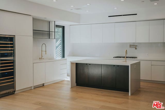 kitchen featuring wine cooler, white cabinets, and light wood-type flooring