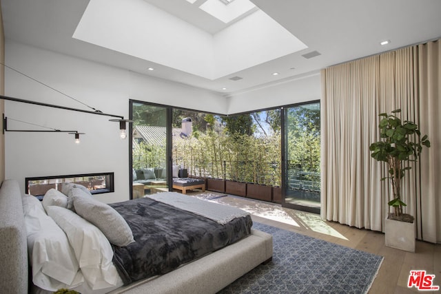 bedroom with multiple windows, a skylight, and hardwood / wood-style flooring