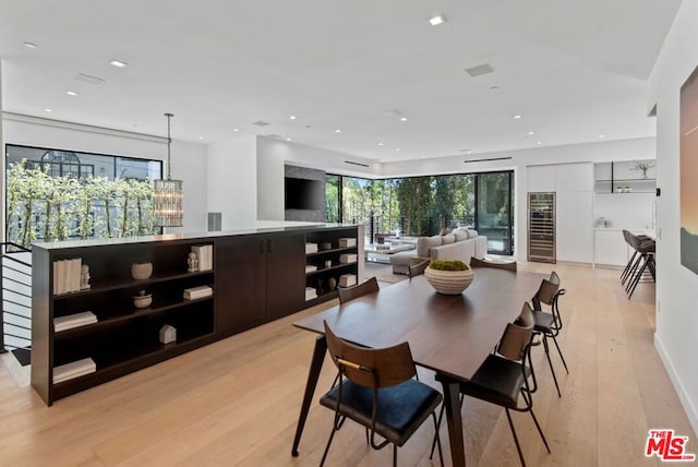 dining space with a chandelier, light hardwood / wood-style flooring, and beverage cooler