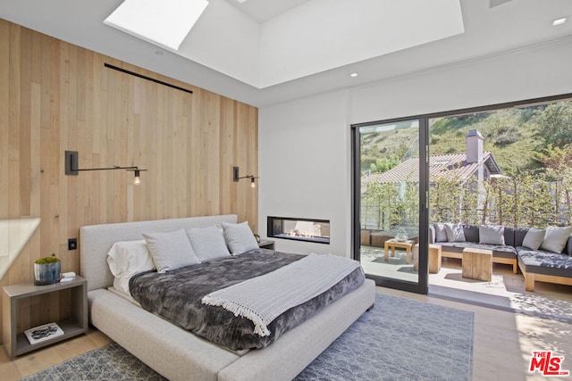 bedroom featuring wood-type flooring, a skylight, and wooden walls