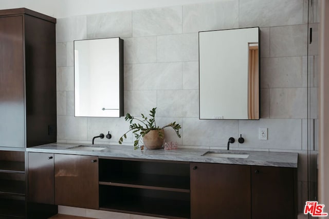 kitchen with tile walls, light stone counters, sink, and dark brown cabinets