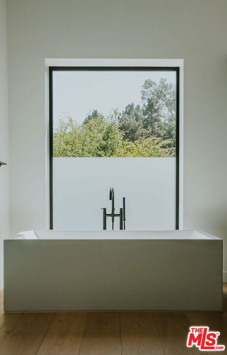 bathroom with a tub to relax in and hardwood / wood-style floors