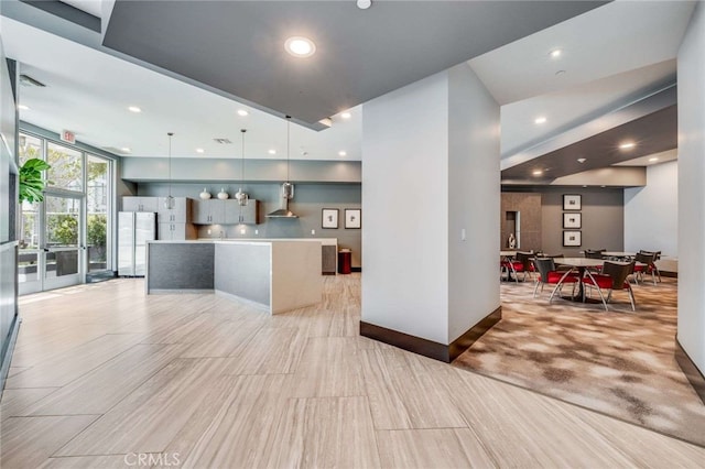 kitchen with pendant lighting, white refrigerator, wall chimney exhaust hood, and a center island