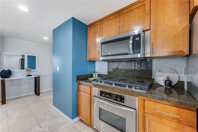 kitchen featuring dark stone counters, stainless steel appliances, backsplash, and light tile patterned floors