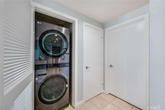 laundry area with light tile patterned floors and stacked washer and clothes dryer