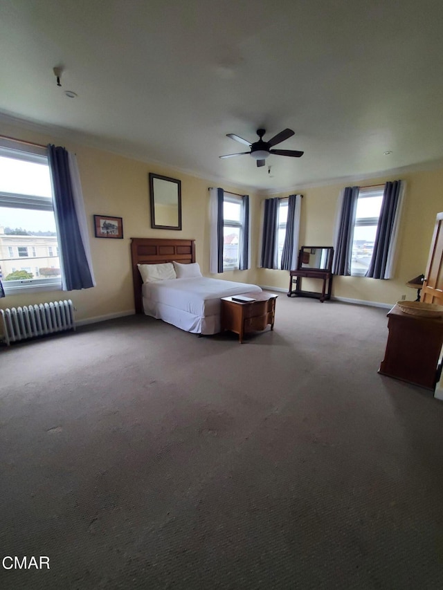 unfurnished bedroom with ceiling fan, radiator, carpet floors, and multiple windows