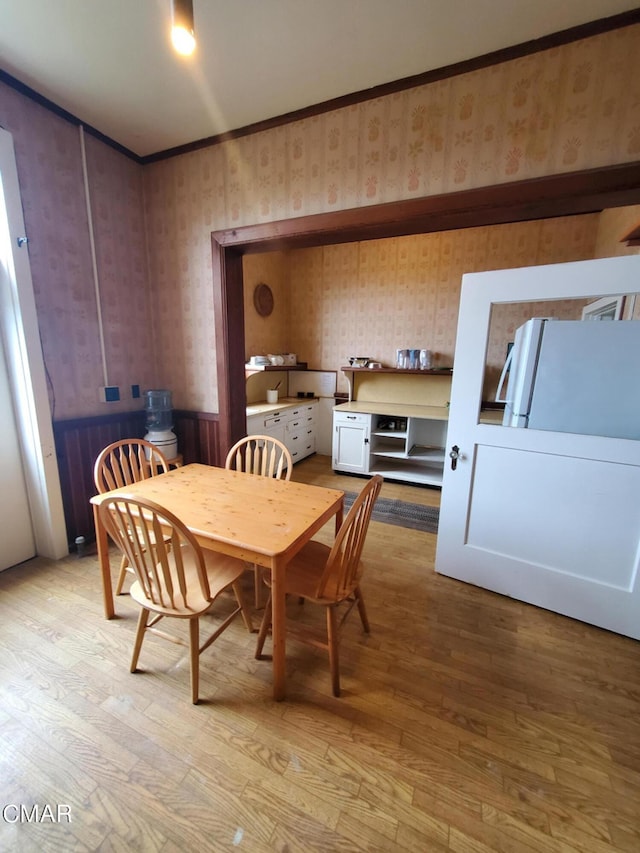 dining room with ornamental molding and light hardwood / wood-style floors