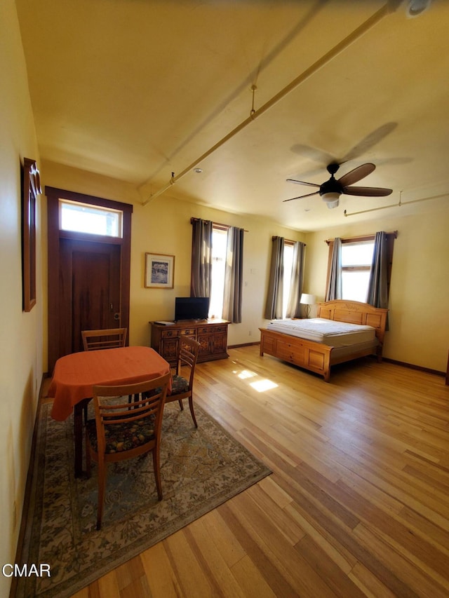 bedroom with ceiling fan, light hardwood / wood-style floors, and multiple windows